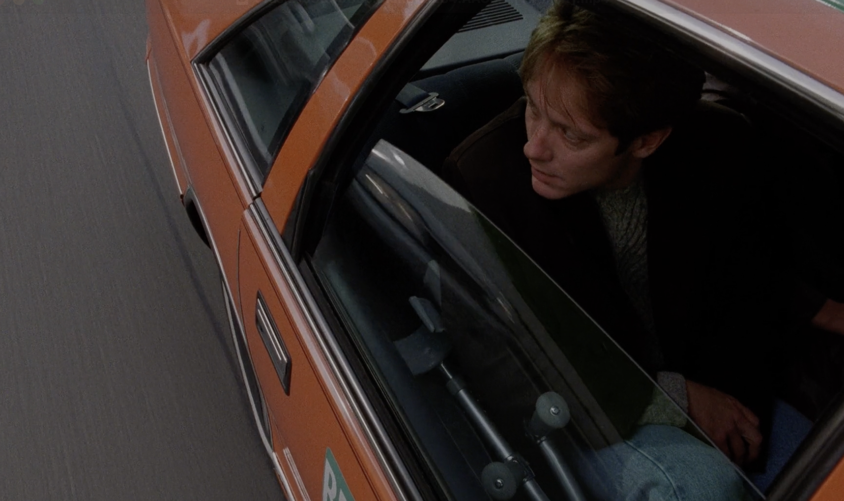 James (James Spader) sits in the backseat of a taxi. Through the rolled-down window, he watches other cars fly by.